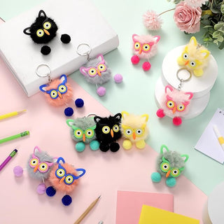 Kawaii owl plush keychains in multiple pastel colours displayed on a pastel desk