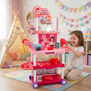 Child playing with a toy hair dryer beside a pink beauty salon trolley